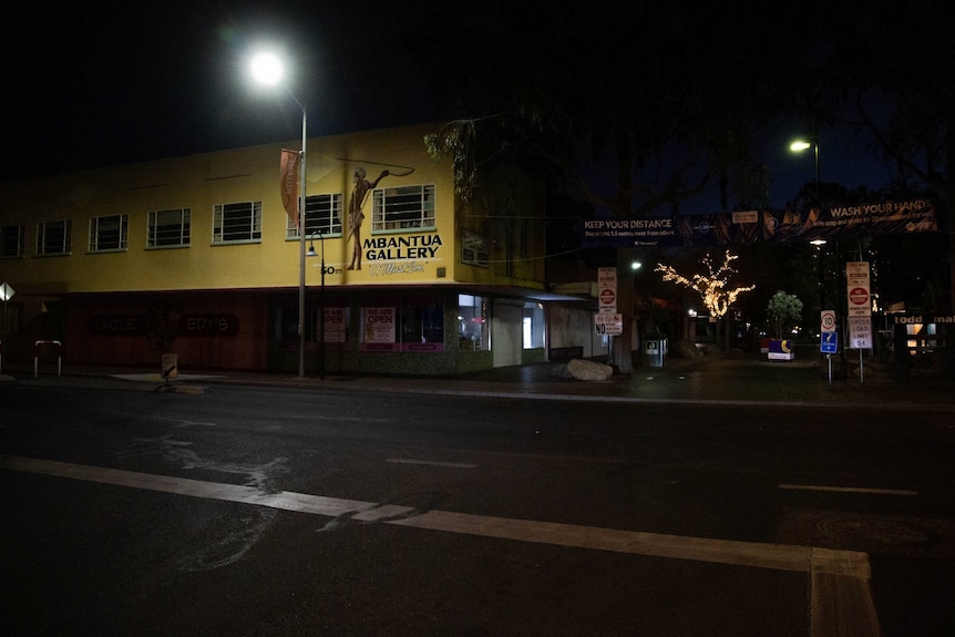 A photo of the Alice Springs CBD at night. A streetlight, the 'Mbantua Gallery', fairylights in the mall, darkness.
