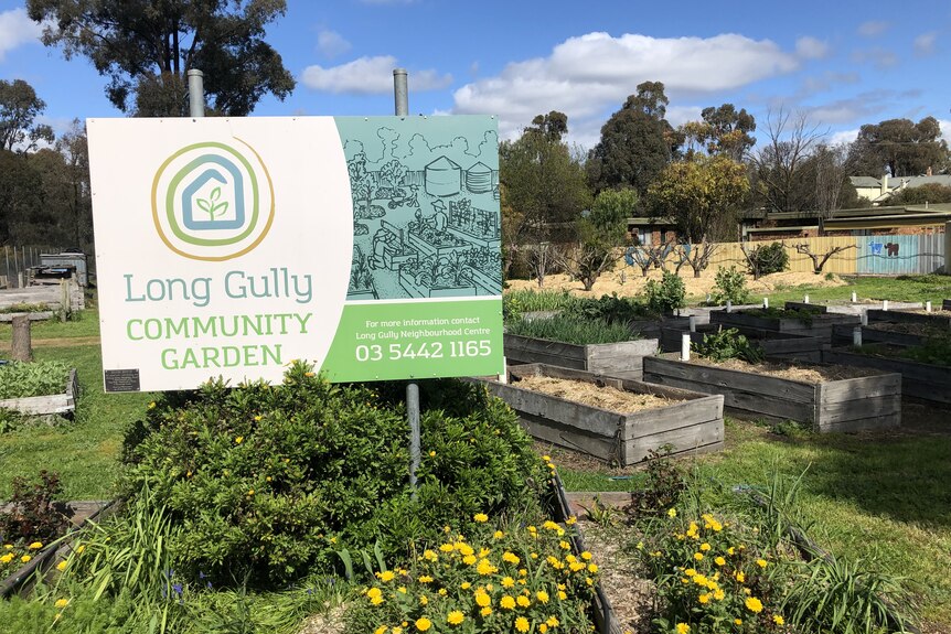 a sign stands in front of garden beds