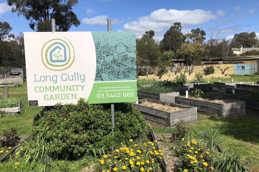 a sign stands in front of garden beds