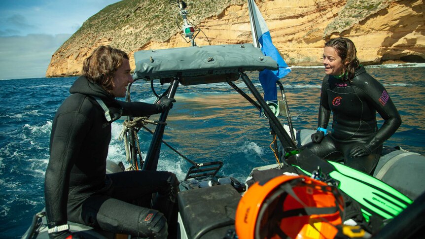 Two marine biologists sit on a rubber boat.