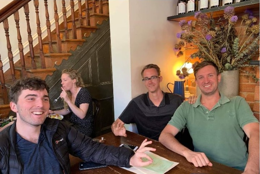 Andrew Wilson and Radiomir Kobryn-Coletti sit at a table, making an alt-right gesture with their hands