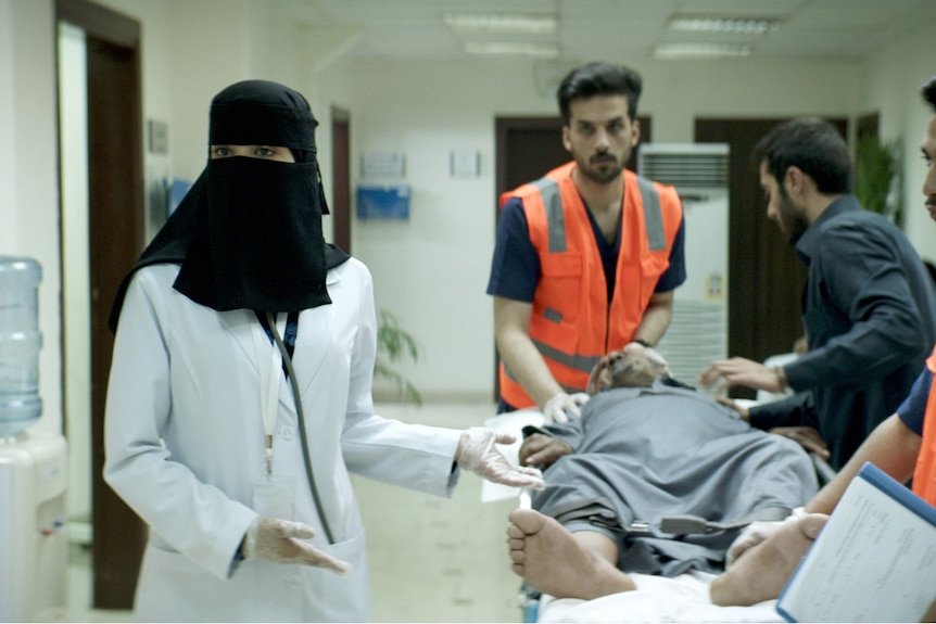 Film still of Mila Al Zahrani as Maryam gesturing to a patient on a gurney in The Perfect Candidate