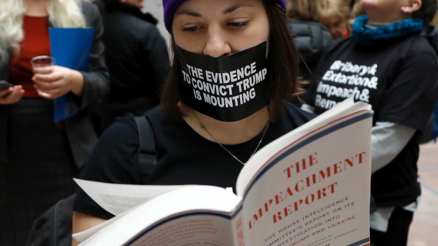 Lindsay Chestnut, of Baltimore, reads the book "The Impeachment Report" while protesting inside the Hart Senate Office Building