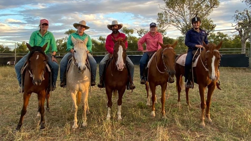 Six people sitting on horses at a cattle station