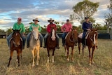 Six people sitting on horses at a cattle station