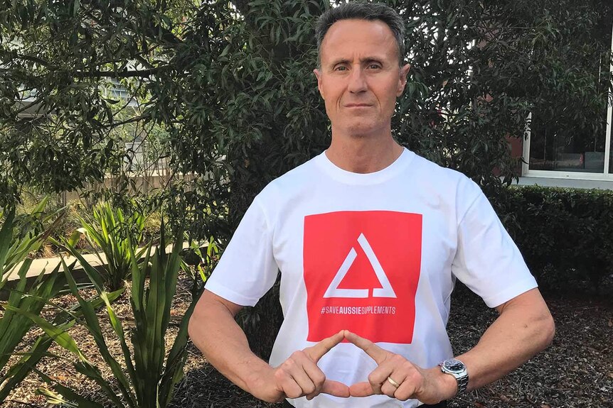 A man in a T-shirt making the shape of a triangle with his fingers to match the symbol on his shirt