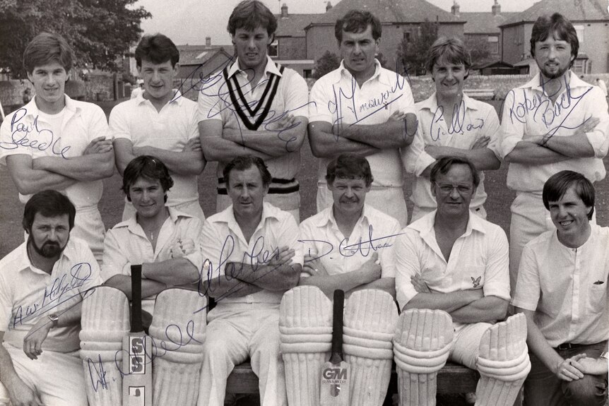 A group of 12 men pose for a cricket team photo.