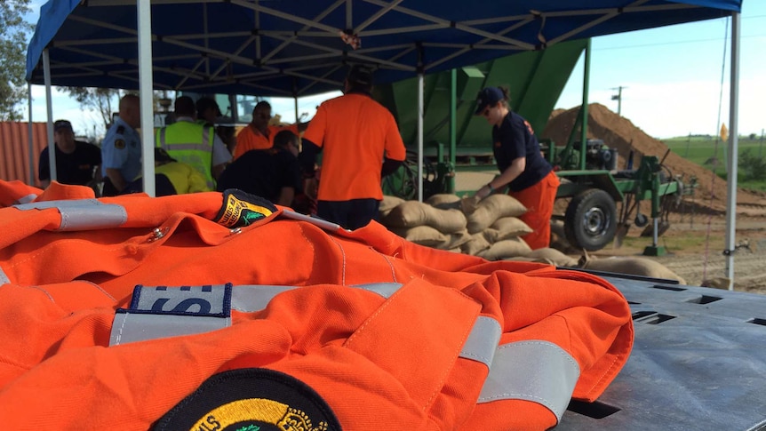 Close up of an orange SES jacket with people sandbagging in the background