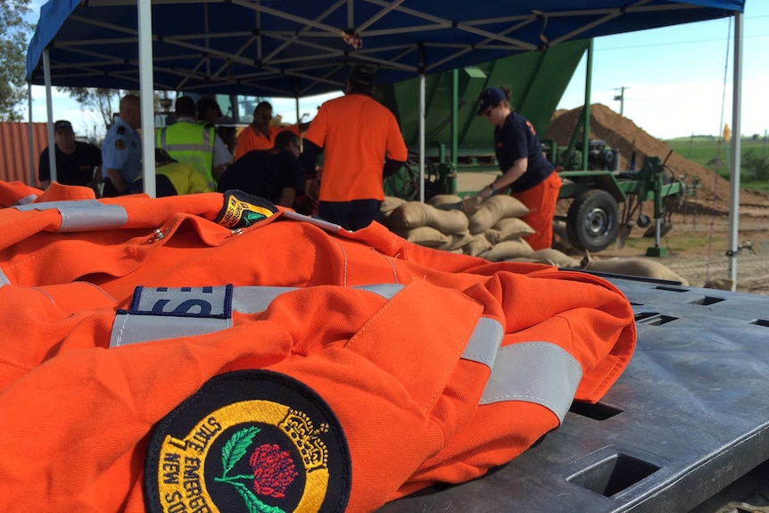 Close up of an orange SES jacket with people sandbagging in the background