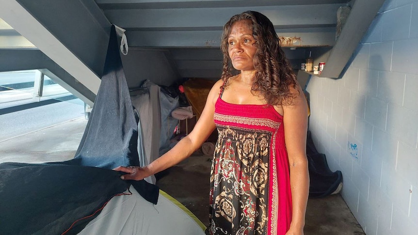 A woman with a tent under a staircase.