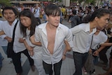 Thai students link their arms as they demonstrate at a shopping mall in Bangkok