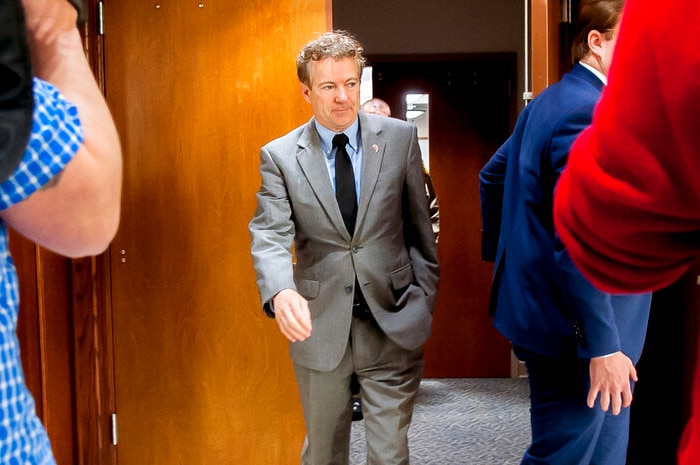 A man in a grey suit leaves a courtroom.