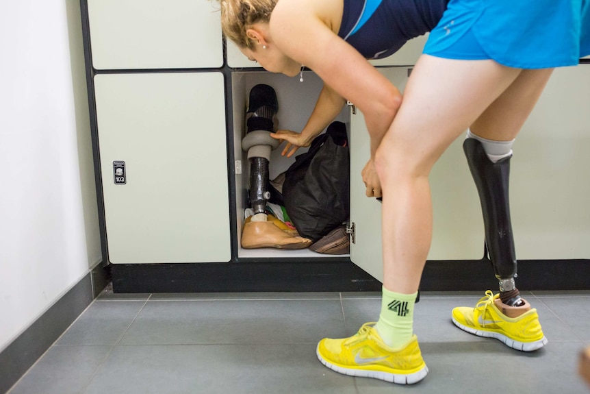 Paralympian Hannah Macdougall retrieves a prosthetic leg from a locker.