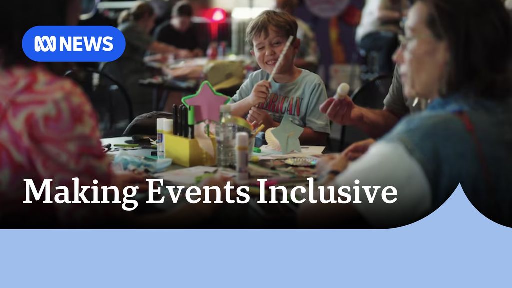 Making Events Inclusive: Young boy winking at camera sits at a table strewn with arts and crafts projects