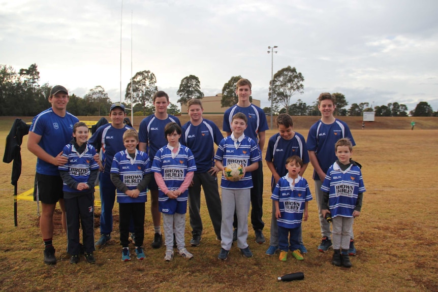 A group of children and their mentors standing in a group for a team photo.