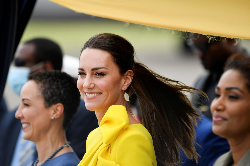 A dark haired woman in a yellow dress 