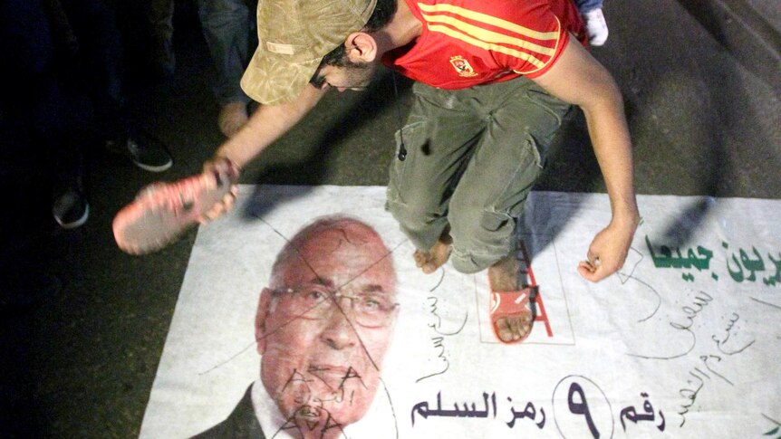 An Egyptian protester hits a portrait of Ahmed Shafiq during a demonstration in Cairo.