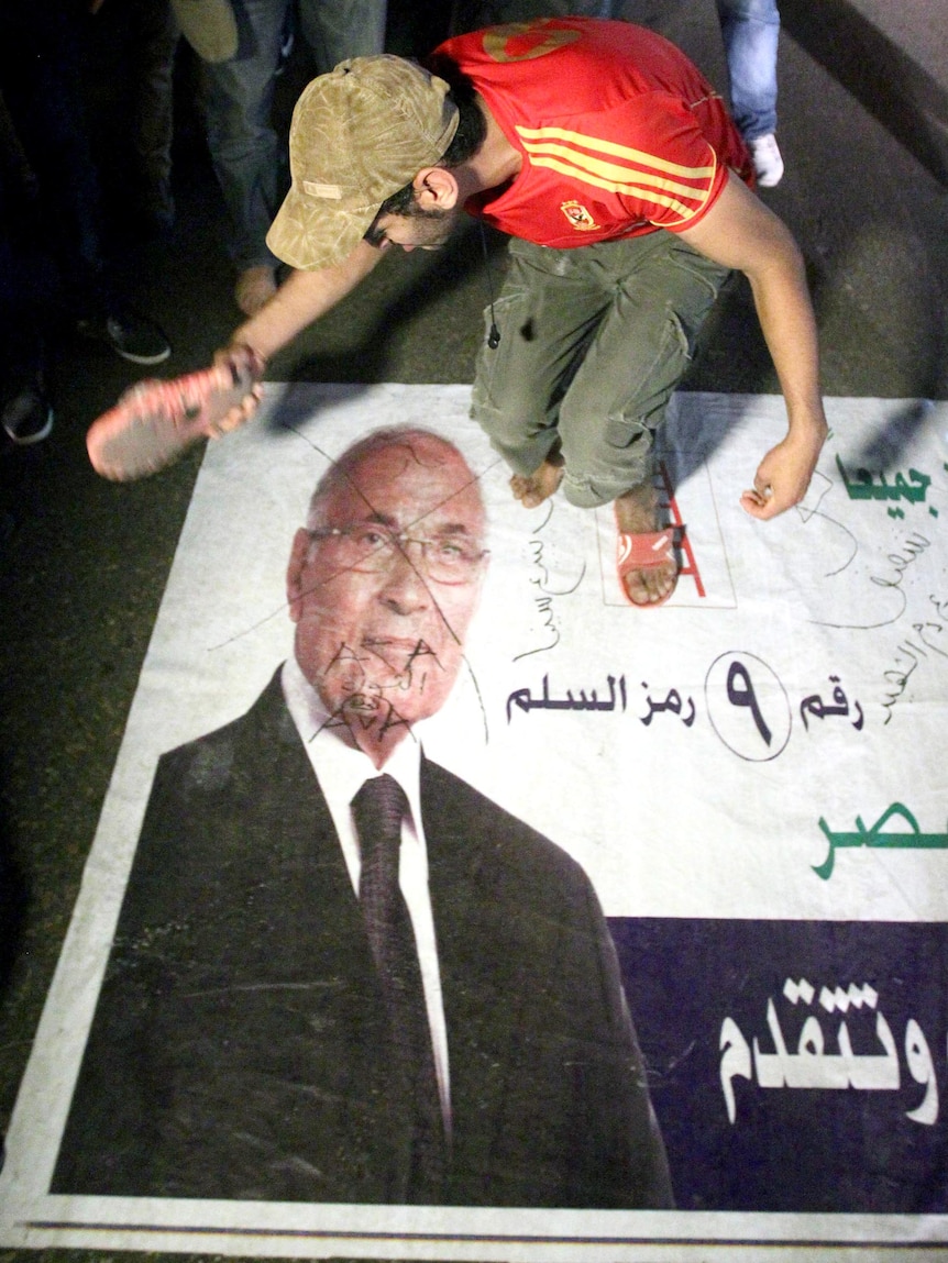 An Egyptian protester hits a portrait of Ahmed Shafiq during a demonstration in Cairo.