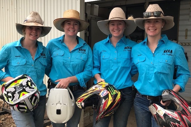 The four Penfold daughters stand in a row, wearing hats and holding helmets.