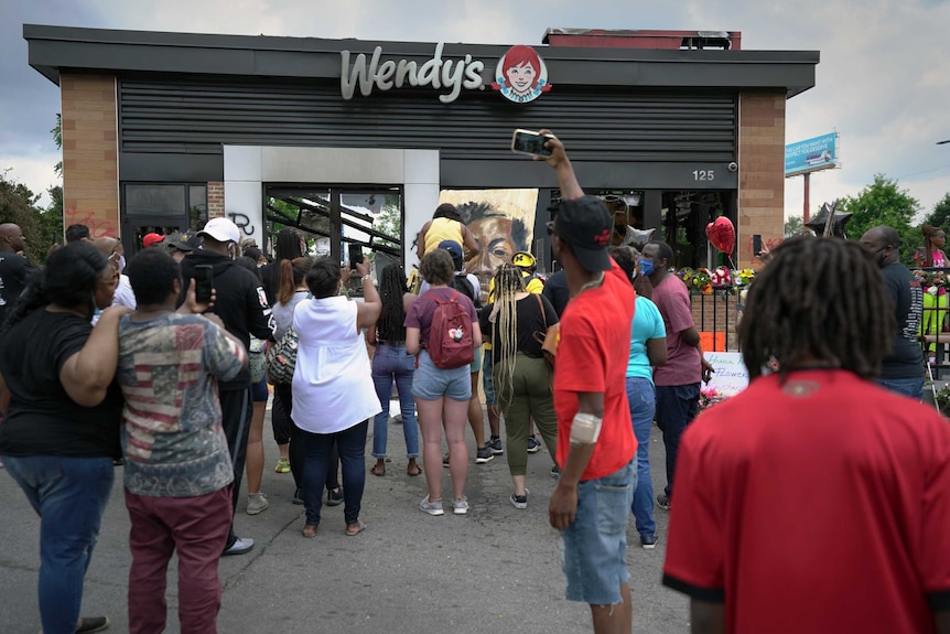 Mourners watch on as a memorial to Rayshard Brooks is being painted.