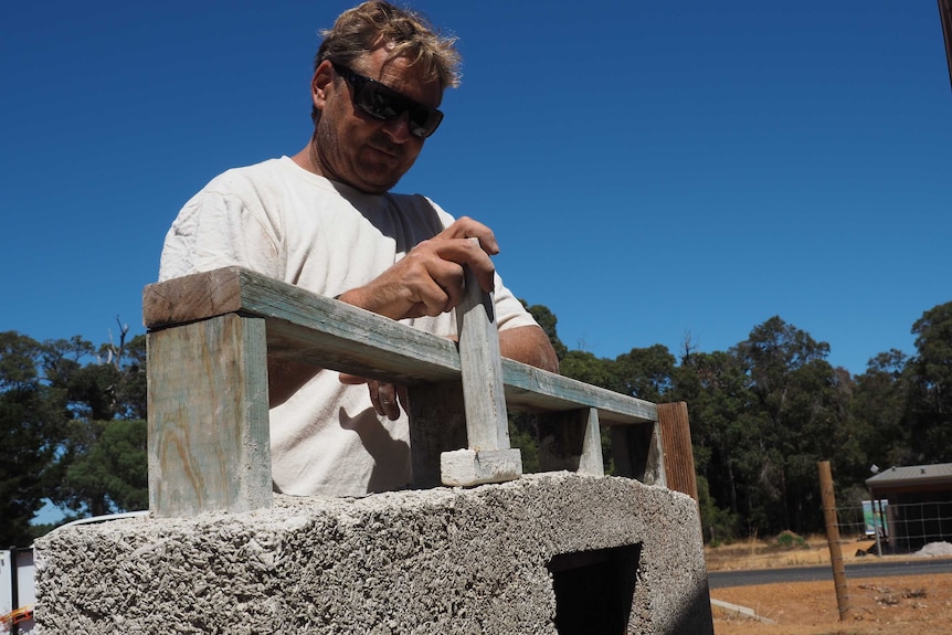 Builder Gary Rogers demonstrates tamping the hemp into place