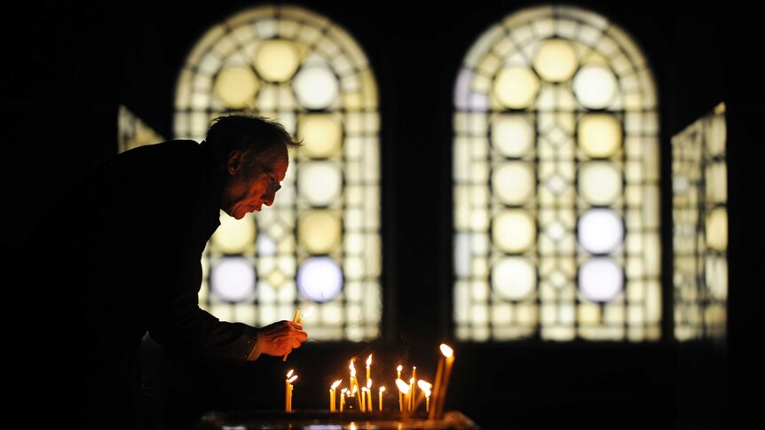 A sexton collects candles during Christmas mass in Alexander Nevsky cathedral in Sofia, Bulgaria.