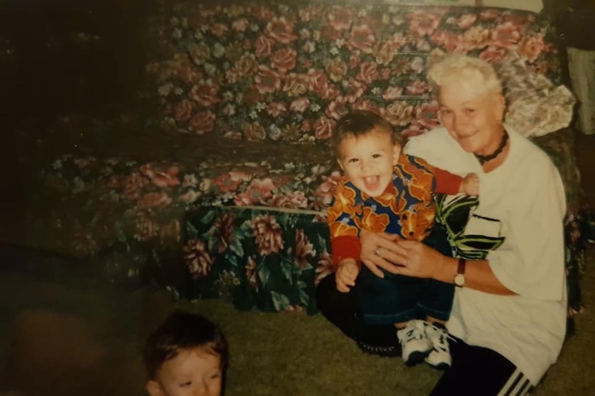 Woman playing with two children in front of a couch