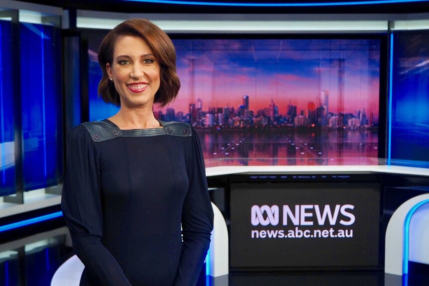 Tamara Oudyn standing in the ABC News studio wearing a navy dress with leather neckline.