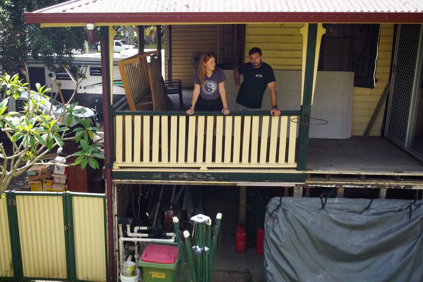 Aerial shot of a man and a woman on the balcony of a house.