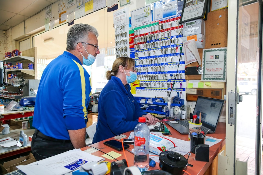 A couple works behind the counter at a hardware store