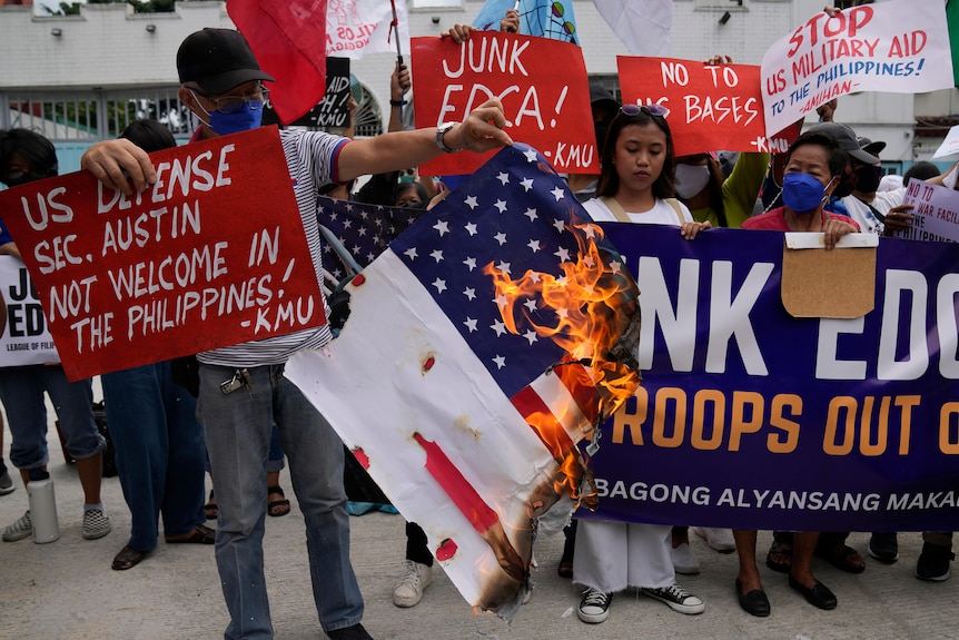 Demonstrators burn a mock US flag as they protest against the visit of US Defense Secretary Lloyd Austin.