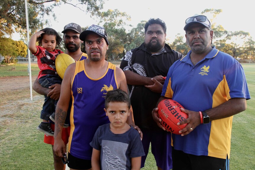 Sam Mitchell with group of Aboriginal football players and their kids.