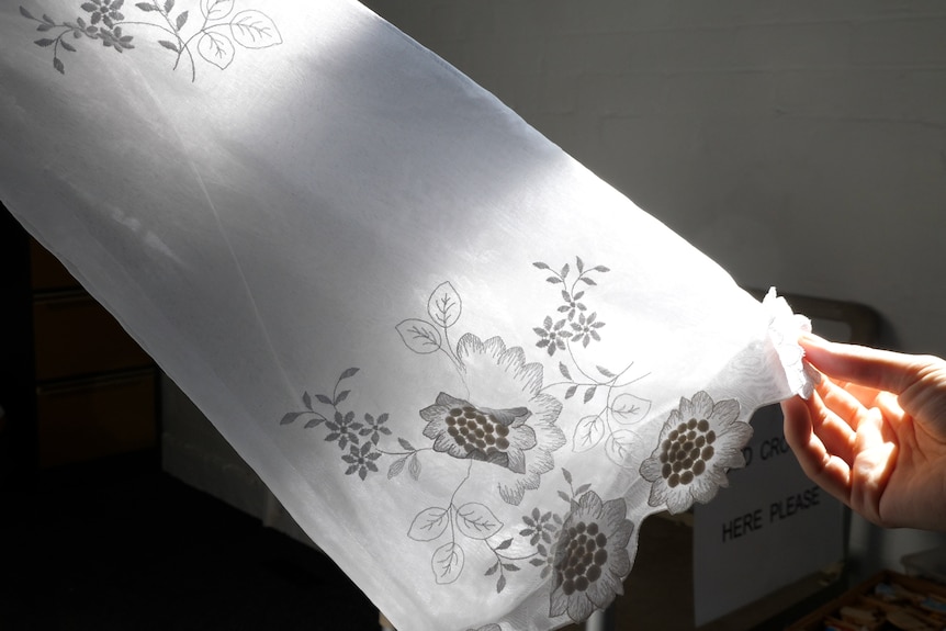 A white wedding dress sleeve with the sun shining behind it with flower appliques
