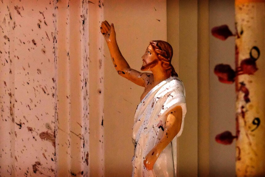 A small statue of Jesus in a church covered in bloodstains.