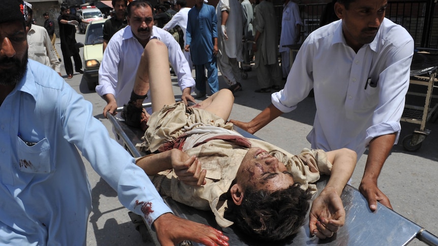 Pakistani men help a blast victim to hospital after a bomb ripped through a bus in Peshawar.