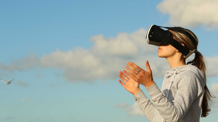 A woman wearing VR goggles outside.