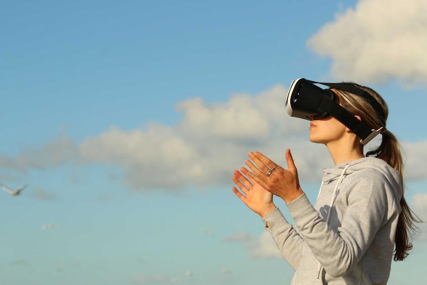 A woman wearing VR goggles outside.