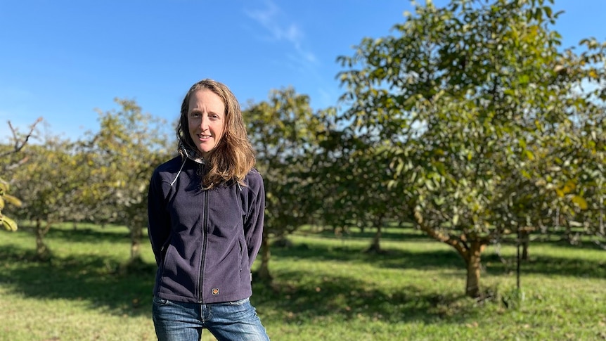 A woman standing in front of a row of walnut trees in Tasmania's Coal River Valley