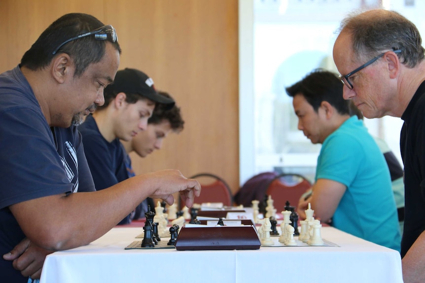 Chess player in the foreground about to make his move.