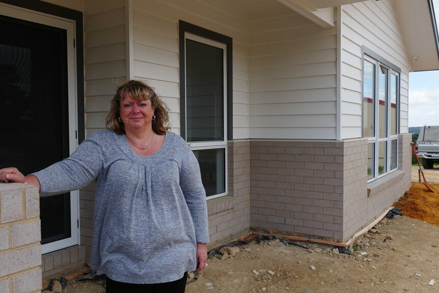 A smiling woman standing in front of a new house