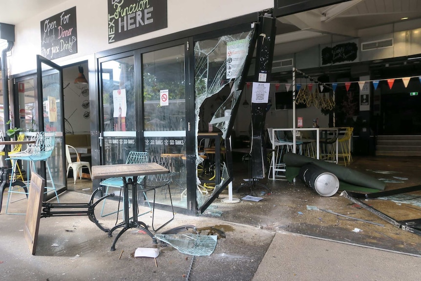 The external wall of Six Tanks Brew Co is seen collapsed with windows shattered and debris scattered across the floor.