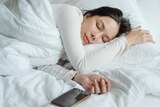 A woman sleeps next to her iPhone. 