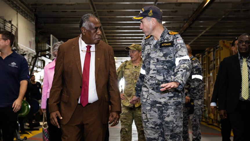 A ni-Vanuatu man and Australian member of defence walk and talk
