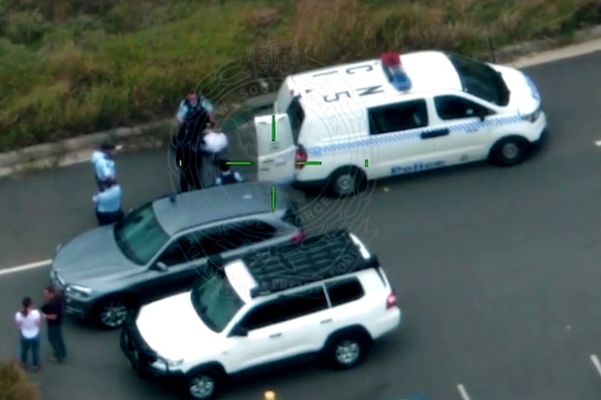 Police arrest a man next to a police van