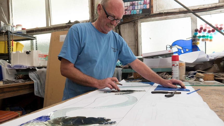 Glass artisan Glenn Howlett works on the lay out of a lead light window.