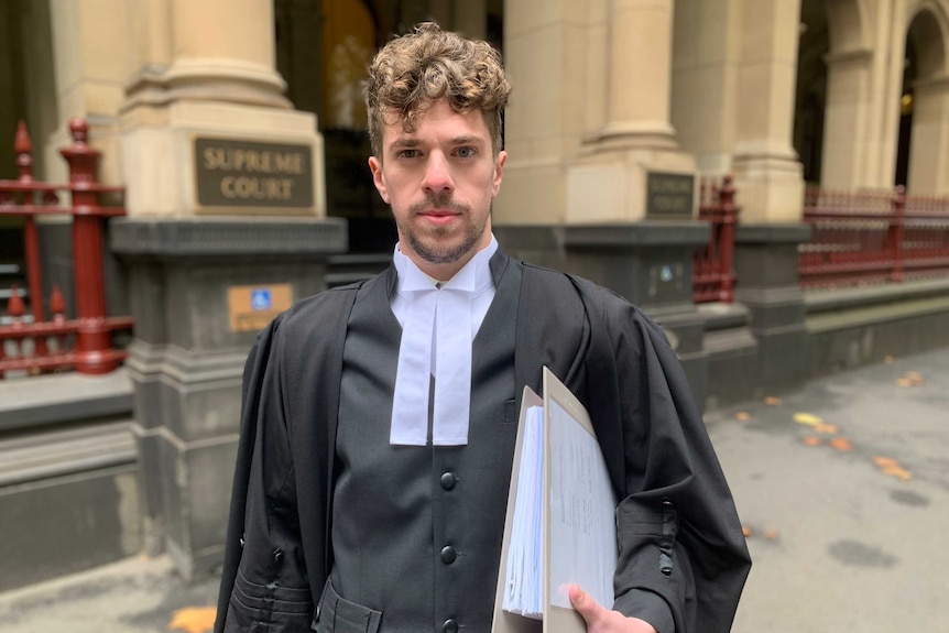 Barrister Fabian Brimfield standing outside a court wearing his legal gown and holding a folder under one arm