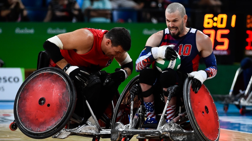 A wheelchair rugby player braces for contact as an opponent speeds toward him.