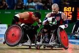 A wheelchair rugby player braces for contact as an opponent speeds toward him.