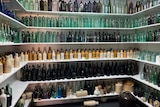 Walls covered in shelves which are filled with old bottles of various shapes and sizes with coloured glass and ceramic.