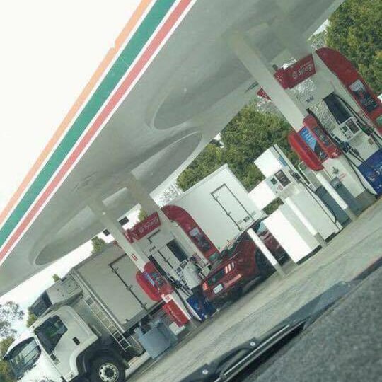 photo of someone filling up a red mustang at a 711 servo